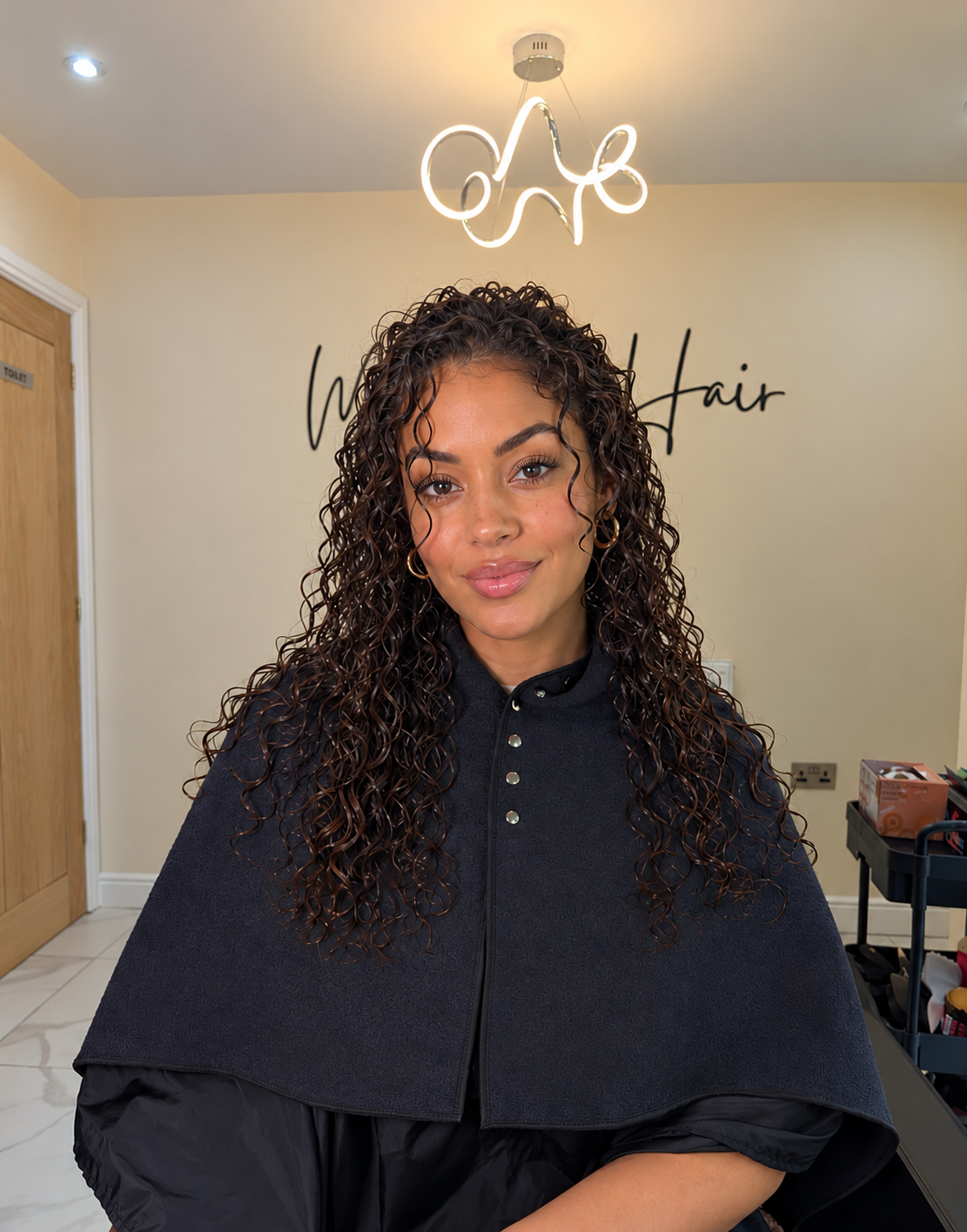 Woman with long wet curls wearing the charcoal IMMY Towel fastened around her shoulders